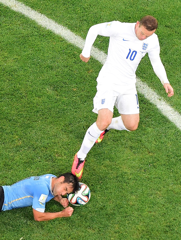 El uruguayo Lodeiro traba de cabeza contra Rooney en el Mundial de Brasil. Foto de la agencia AFP.