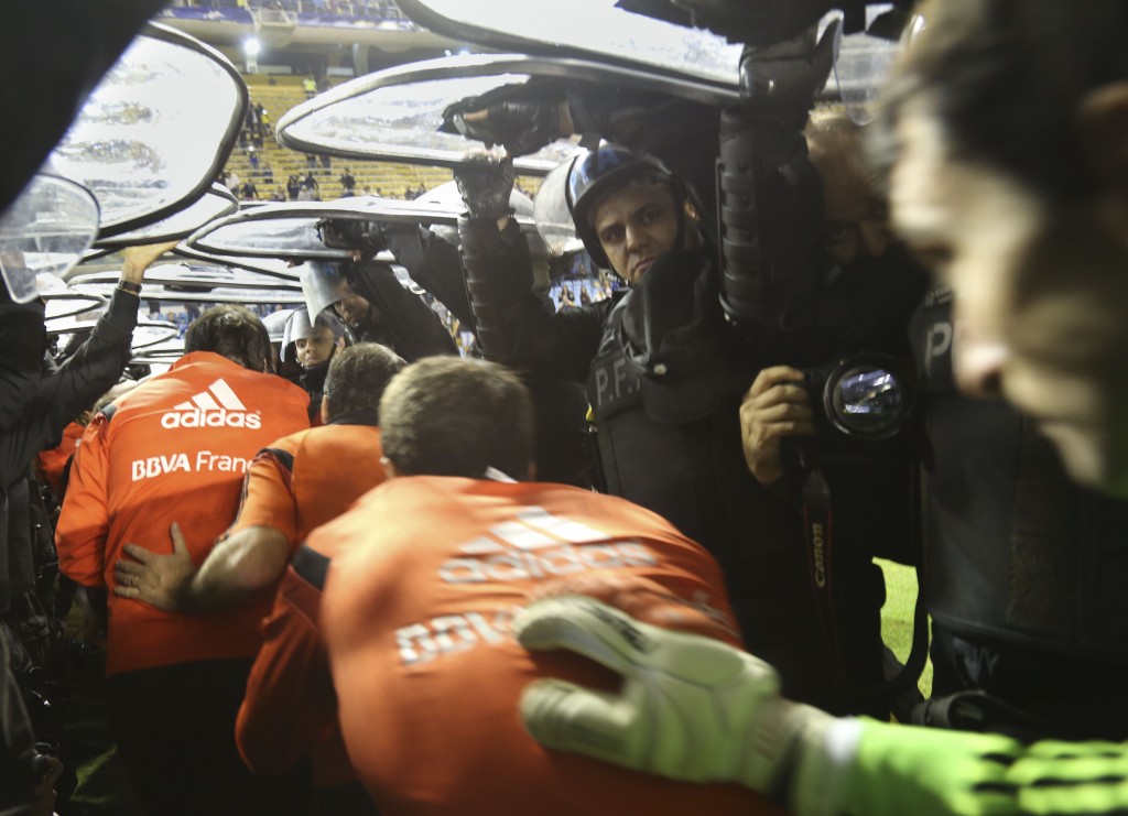 Los jugadores de River se van de la Bombonera en medio de los escudos de la Policía. Foto de Damián Dopacio / Agencia NA.